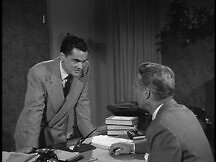 Man talking to Davis in his office, revealing Davis' true identity as Rosseli