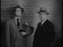 Clark holds Pepi the monkey in an alley while Perry stands nearby