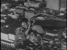 Superman flies over the city with Kathy in his arms